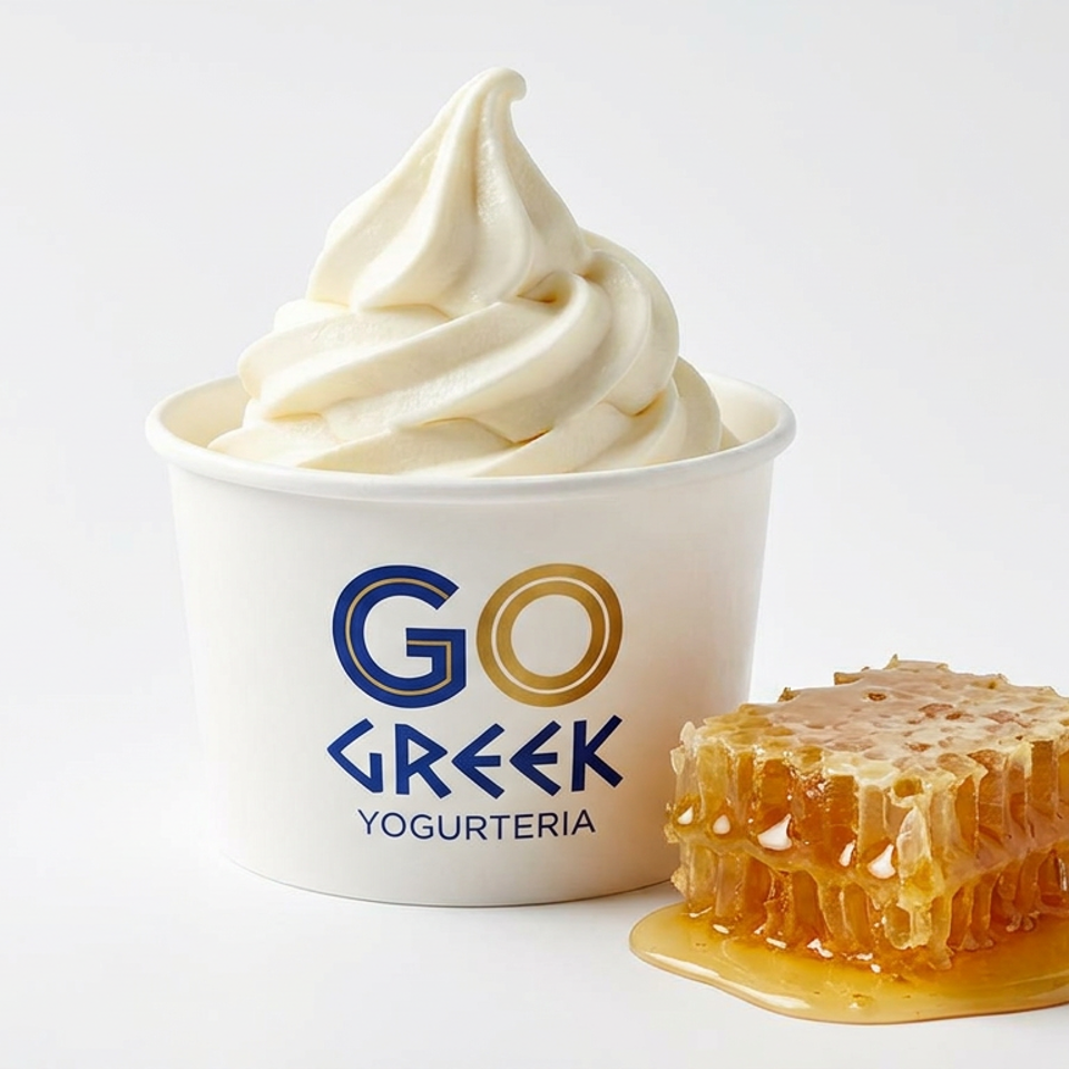 Swirled frozen yogurt in a Go Greek Yogurteria cup beside a dripping piece of honeycomb.